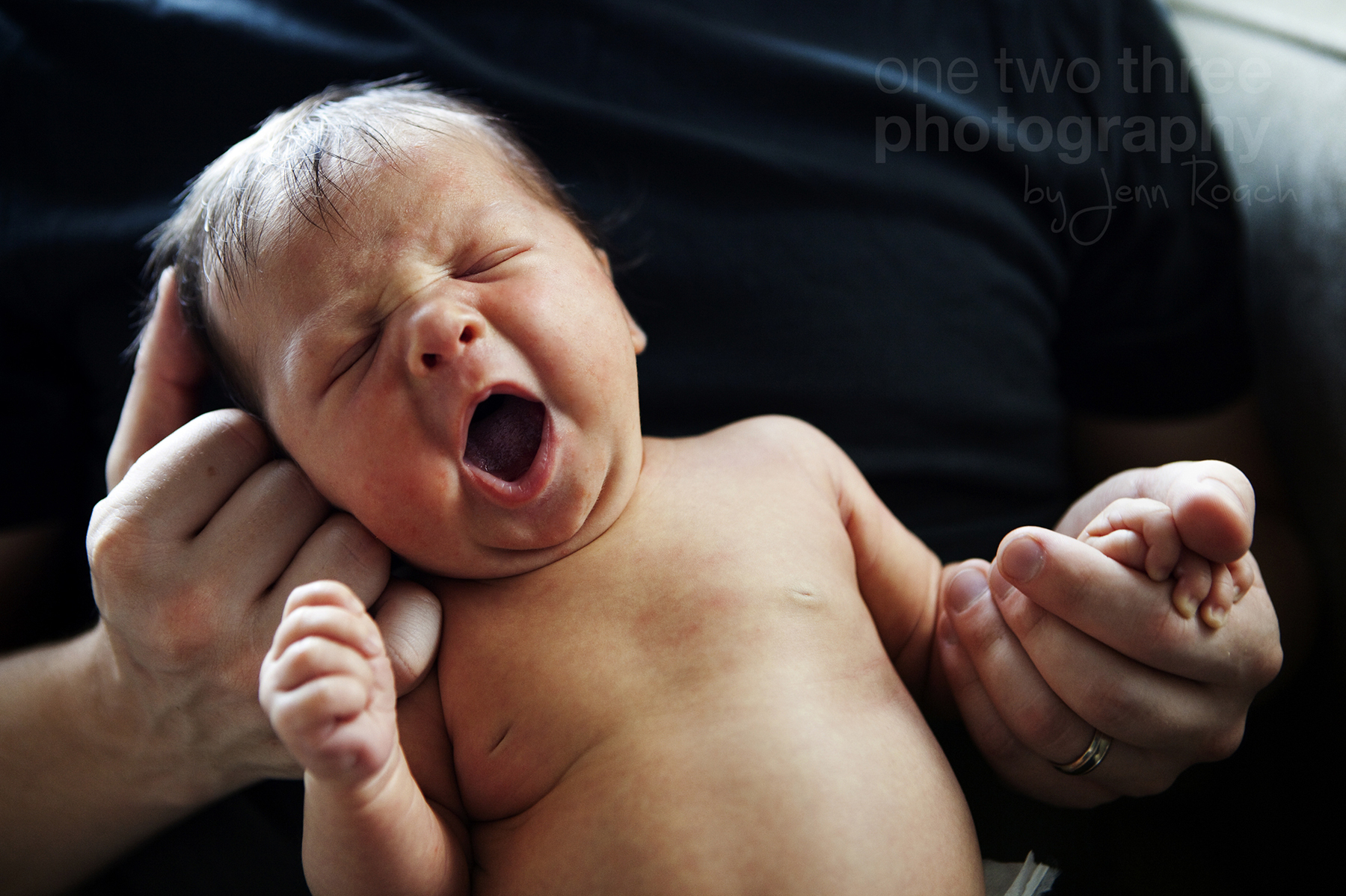 Baby Leah yawns during the photography session in the arms of her father