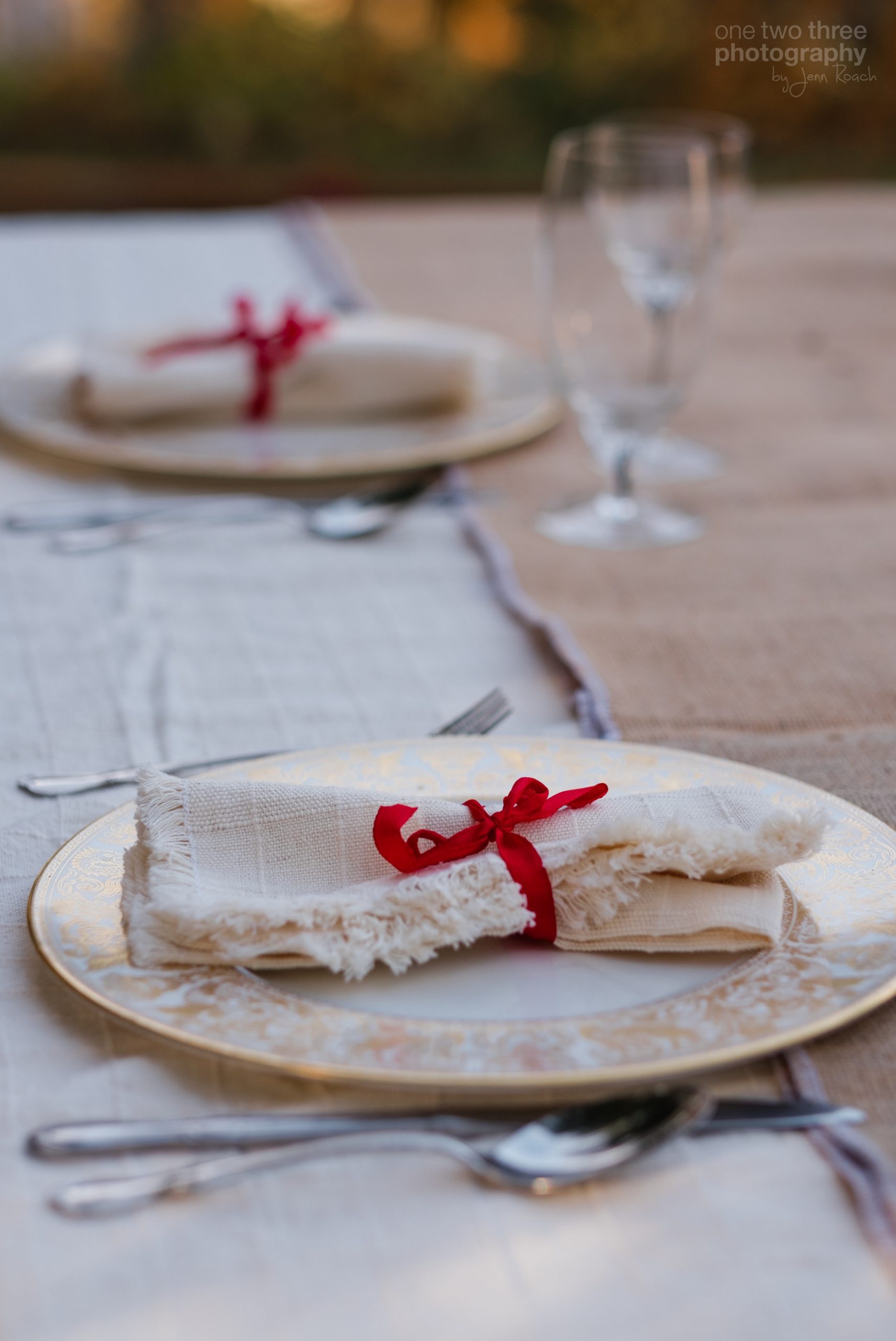 Christmas table place setting with fine china and red ribbon