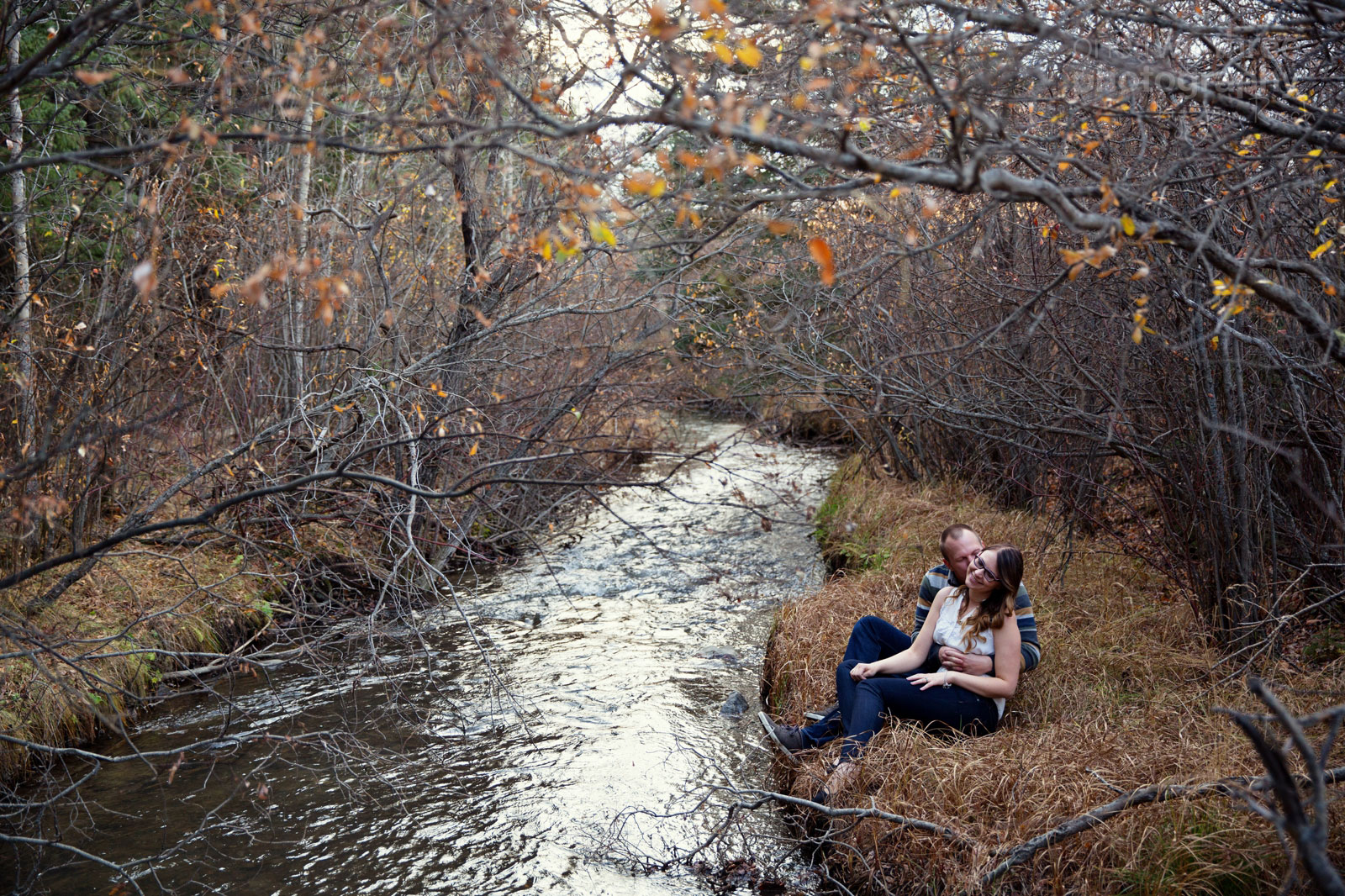 Couple sitting by a small stream in a fall photography shoot